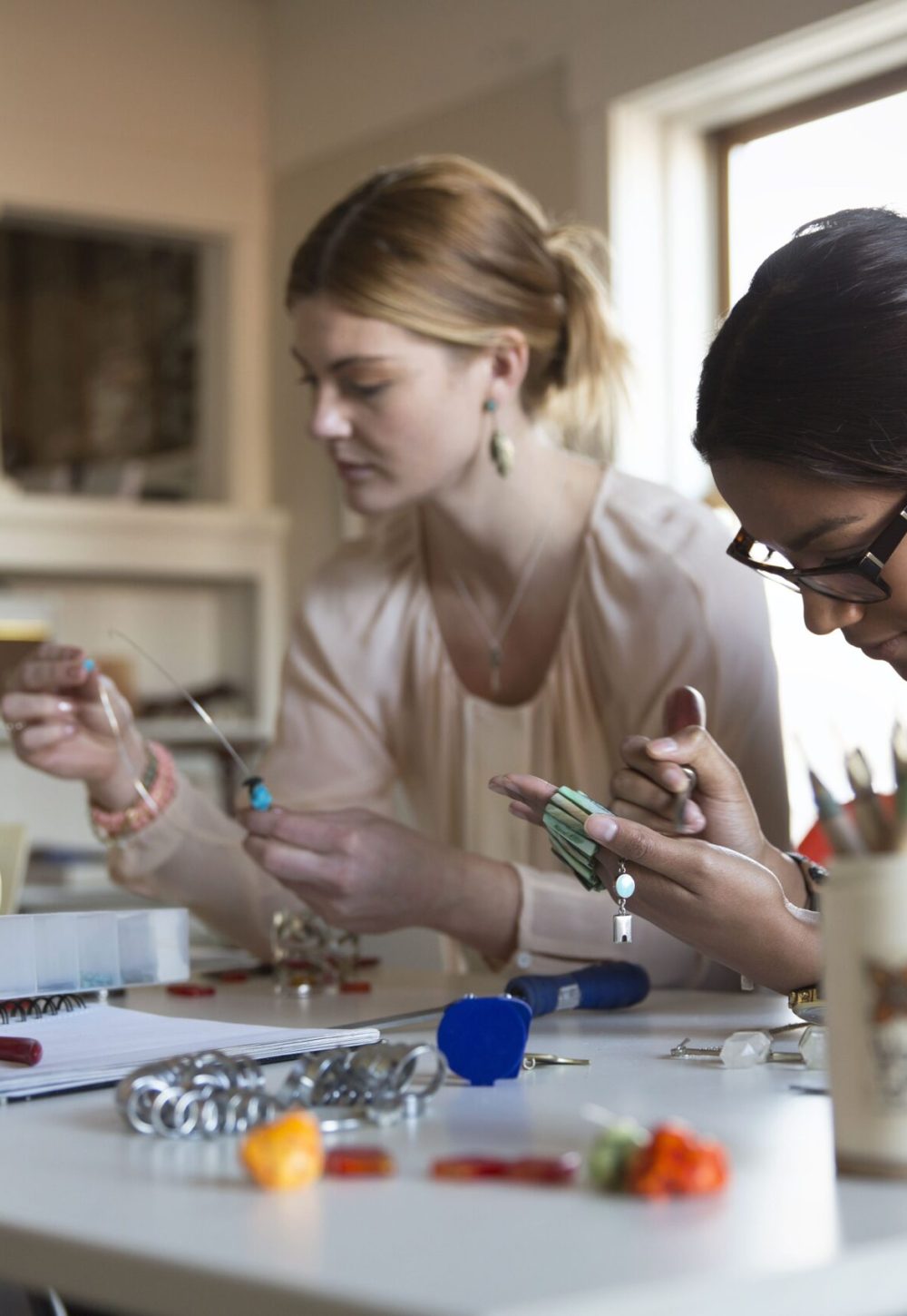 female-colleagues-making-bracelet-and-necklaces-at-desk-168359263-57ea92153df78c690f92fbbe